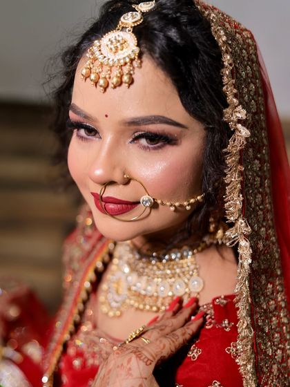A close-up portrait of a bride in red. Her makeup features a sharp winged liner and a perfectly defined red lip, showcasing a classic bridal look.