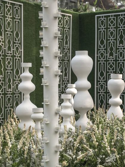 Sculptural white art installations placed amidst flower beds add a contemporary and artistic touch to the garden setting.