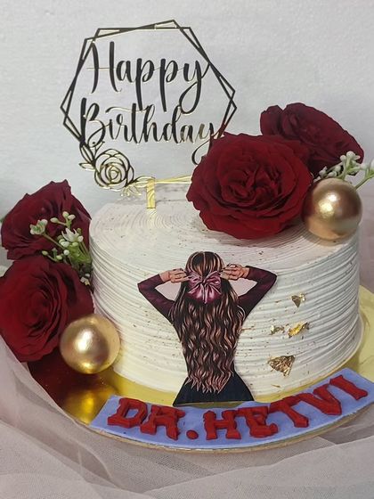 An elegant cake with red roses and a topper for Dr. Hetvi.
