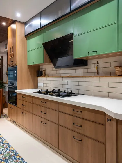 A full view of this warm and functional kitchen, showcasing the balance of wood tones, green accent cabinets, and classic white subway tiles. Every element is chosen to contribute to a cohesive and inviting atmosphere.