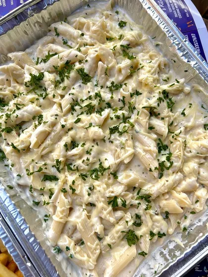 A party tray of my cheesy baked white sauce pasta, garnished with fresh parsley. This is a perfect dish for bulk orders, loved by both kids and adults.