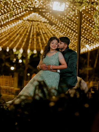 I love using creative lighting to create a magical atmosphere for evening events. Here, a canopy of fairy lights provides a warm, romantic glow for an intimate reception portrait, highlighting the couple's connection.