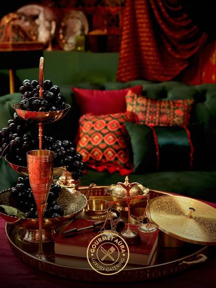 A tiered fruit stand with grapes and elegant glassware, part of a richly decorated lounge area.