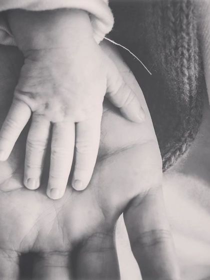 A powerful black and white image showing a newborn's hand resting in their parent's palm. This photo beautifully illustrates the scale and the instant, profound connection.