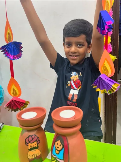 This student is excited to show off both his painted tea-light holders and the colorful paper hanging he made.
