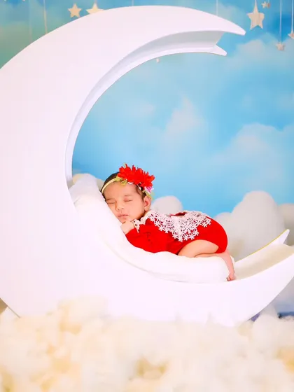 A wider angle of the newborn on the white moon prop, showing the dreamy cloud and sky setup in our studio.