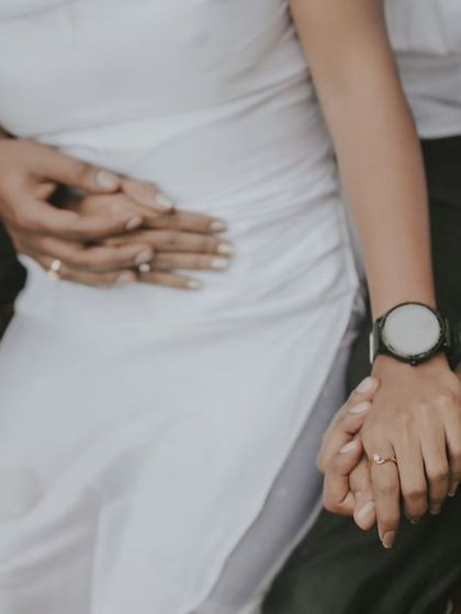 A detail shot focusing on the couple's hands and embrace during their water photoshoot. This highlights intimacy and connection without showing faces.