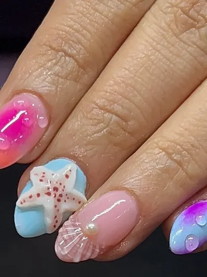 Holiday nails, beach edition. This set features 3D elements like a starfish, a seashell, and water droplets for a fun, textured look.