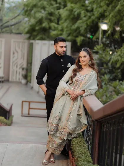 A stylish portrait of the couple on a bridge, showcasing their coordinated outfits and confident poses.