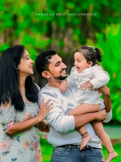 A happy family of three enjoying a moment in a lush green park. The vibrant background and their joyful expressions make for a perfect candid family portrait.