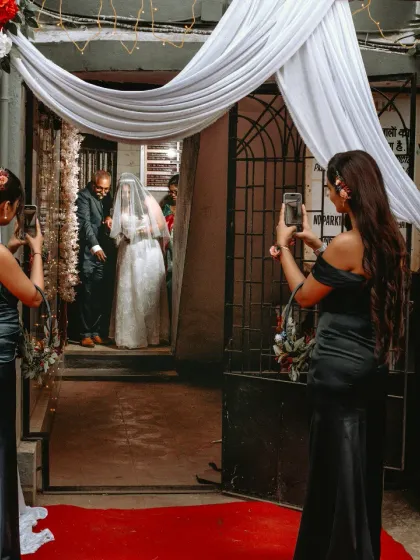 A behind-the-scenes shot of the bridesmaids capturing the bride's entrance on their phones. A modern wedding moment.