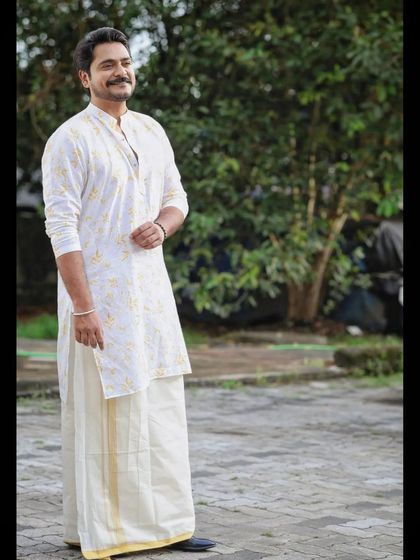 Actor Kalesh Ramanand styled in a classic white kurta and mundu for a traditional photoshoot. We focused on a clean, sharp hairstyle and natural makeup.