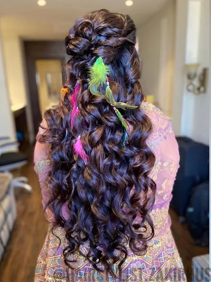 For a fun and festive Mehendi or Haldi look, I love incorporating unique accessories. This half-up curly style is accented with colorful feathers, adding a playful and vibrant touch to the celebration.
