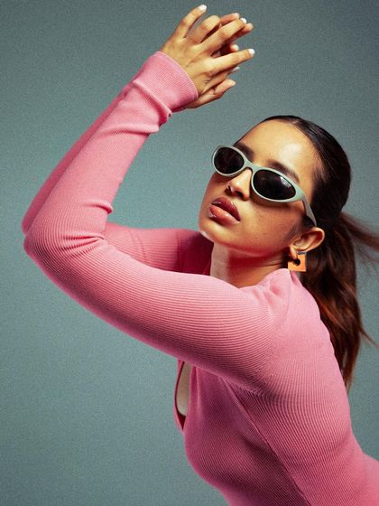 A dynamic shot capturing movement. The model's pose and the slight motion in her hair add energy to this studio fashion portrait, showcasing the outfit in an active, engaging way.