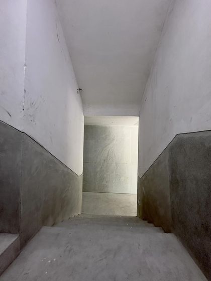 Looking down a narrow, unfinished concrete corridor.