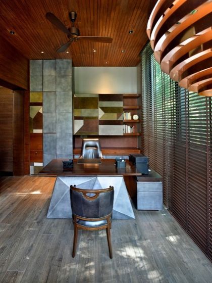 The interior of the cantilevered study, featuring a custom-designed desk and a rich palette of wood and metal. The space is crafted to be a sanctuary for focus and inspiration, sheltered by the canopy of a large tree.