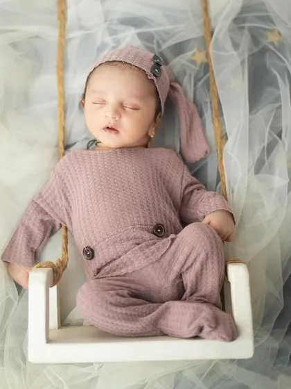 A full view of the newborn peacefully sleeping on the swing prop. My studio is equipped with a variety of safe and creative props to make your baby's first photoshoot special.