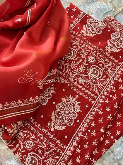 A flat-lay of the complete red suit, showing the ombré dyed dupatta and the heavily worked kurta.