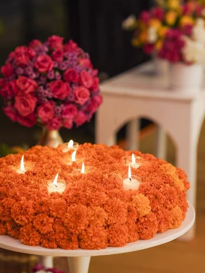 The marigold and candle centerpiece seen from another angle, with elegant white furniture and bouquets of pink roses in the background.