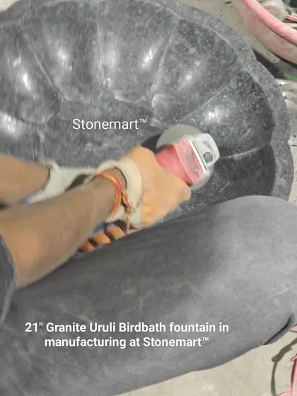 An artisan uses a grinder to smooth the interior of a 21-inch granite urli birdbath fountain. This shows the final stages of production for this popular masterpiece.