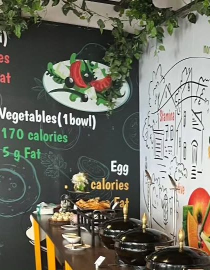 A buffet setup for a corporate event with a health-conscious theme. The wall art displays nutritional information, and the menu is designed to be both delicious and wholesome.
