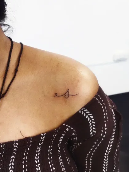 A simple, elegant initial 'S' on the collarbone. A subtle and personal piece.
