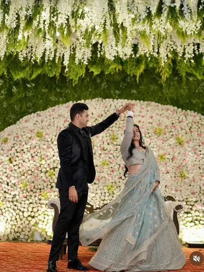 The same couple sharing a dance in front of the beautiful floral wall, with a ceiling of hanging white flowers creating a dreamy, romantic atmosphere.