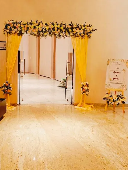 A simple and elegant entrance for an engagement party, with a yellow floral arch and a matching welcome sign to greet guests.