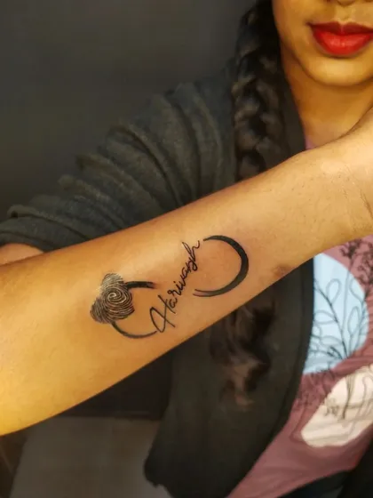 This tattoo weaves the name "Harivansh" into an infinity symbol that ends in a rose. It's a creative way to symbolize eternal love.