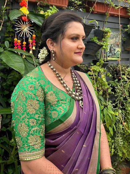 A side profile of the client in her green and purple ensemble, showing the rich texture of the embroidered blouse.
