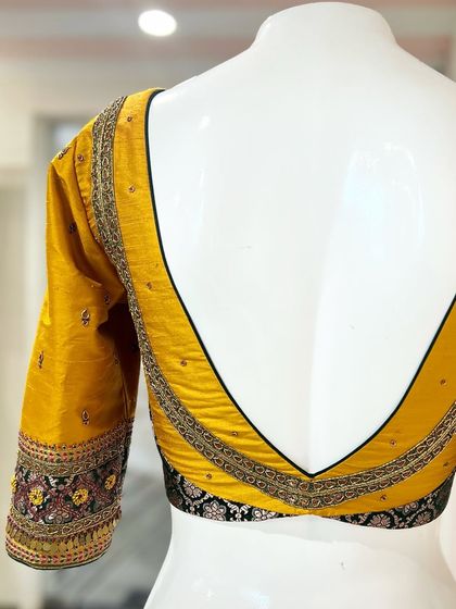 The dramatic deep V-back of the yellow and black statement blouse, showcasing its bold design.