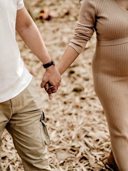 A close-up shot of the couple holding hands as they walk through the woods. This detail emphasizes their partnership and the journey they are taking together.
