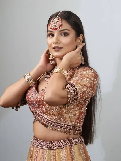 This pose highlights the beautiful detailing of the 'Riwayat' look, from the maang tikka to the bronzed cheeks. It's a look that feels regal and effortlessly beautiful.