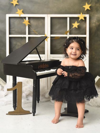 A classic first birthday portrait at the piano. The simple yet sophisticated set allows her sparkling personality and beautiful black dress to take center stage.