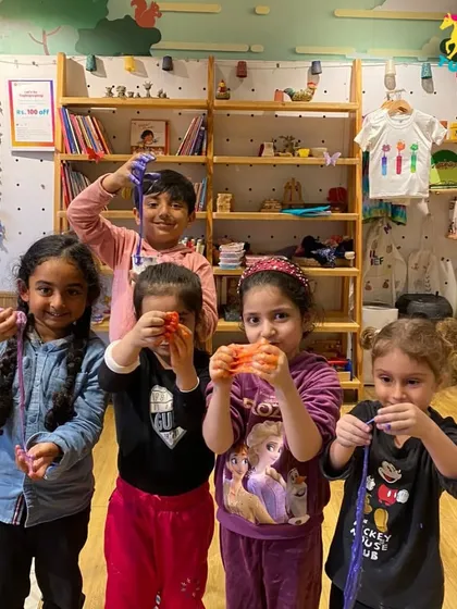 A group of girls proudly showing off their colorful, stretchy slime. The sense of accomplishment after a successful experiment is a huge confidence booster.