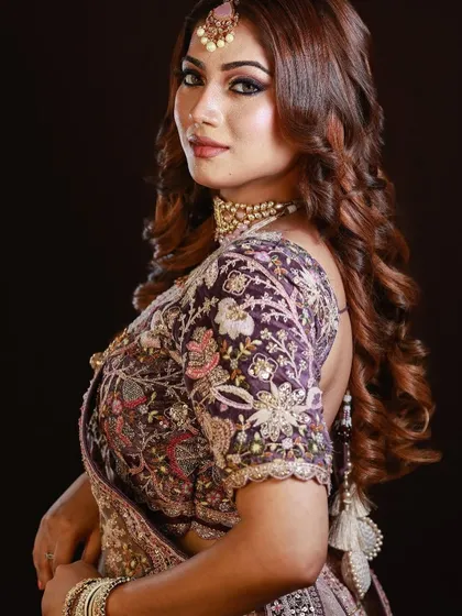 A side profile showing the intricate embroidery of the blouse and the soft, romantic hair and makeup.