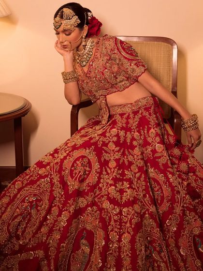 Presenting Nazaakat. A bride in a heavily embroidered red lehenga, seated in a vintage-inspired setting.