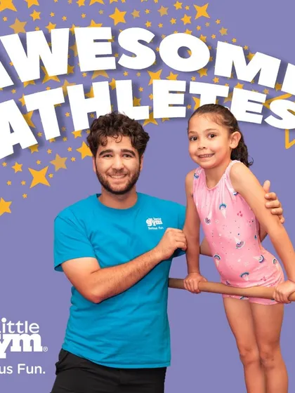 An instructor and a young 'Awesome Athlete' share a moment of connection at the bar. This supportive relationship is crucial for helping children feel safe and confident.
