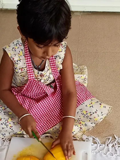 Deep in concentration, this little one is mastering the practical life skill of slicing fruit. Using child-safe tools, we empower children to perform real-world tasks, building their confidence and independence.