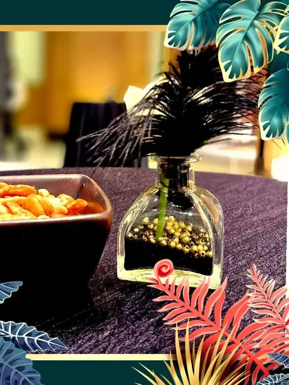 A simple yet elegant centerpiece featuring a black feather in a glass bottle with gold beads. This small detail, placed on guest tables, reinforces the 1920s theme with a nod to flapper-era style.