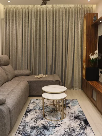 A comfortable living room setup with a recliner sofa and a wooden TV unit. The abstract rug and nested center tables add a modern touch to the cozy space.