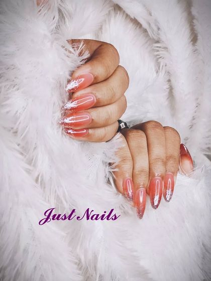 A dramatic set of stiletto extensions with a sheer pink base and sparkling glitter tips.