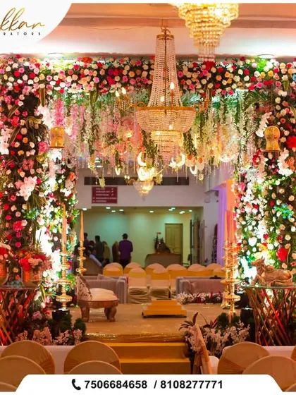 A grand floral mandap entrance featuring a massive chandelier. The abundance of fresh flowers creates a luxurious and welcoming atmosphere for the wedding ceremony.