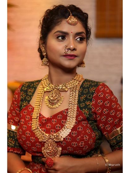 A classic three-quarter portrait, focusing on the rich details of the jewelry and the patterned fabric of the dress.