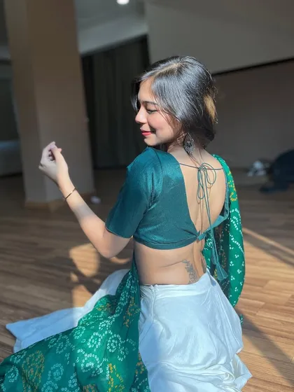 A graceful pose in a green and white saree, capturing a moment of quiet elegance.