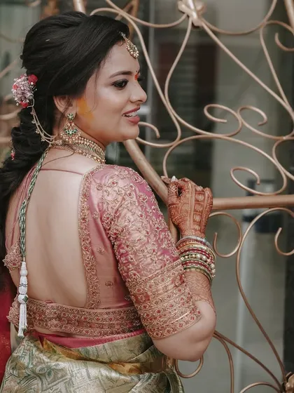 This bride's pink blouse features a deep, open back with exquisitely detailed embroidery along the borders and sleeves. The design is perfect for showcasing intricate hairstyles and jewelry.