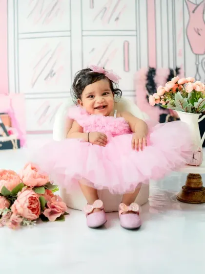 The perfect half-birthday portrait, capturing a huge, happy grin. The combination of the pink tutu, flowers, and pearls creates a beautifully coordinated and girly theme.