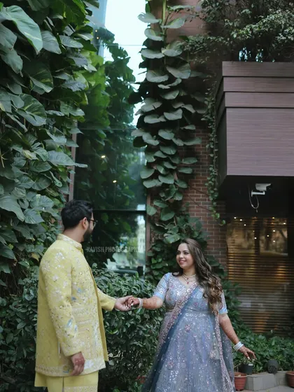 A candid moment between a couple at their wedding, set against a stunning wall of green foliage.