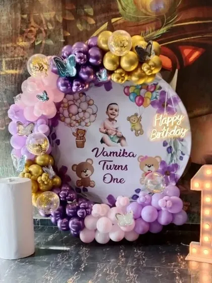 A teddy bear themed first birthday party with a custom photo backdrop and a '1' marquee light.
