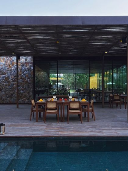 The pavilion set for dinner, with the pool reflecting the warm lights of the evening.